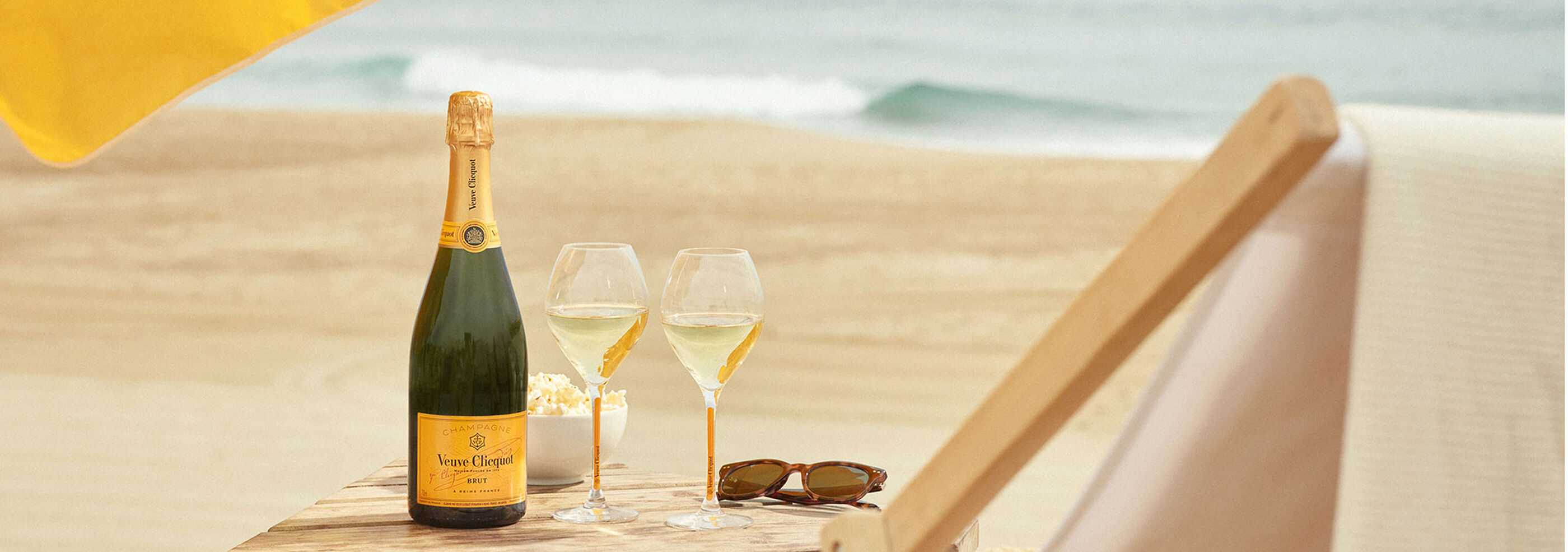 Veuve bottle at beach with glasses and sunglasses